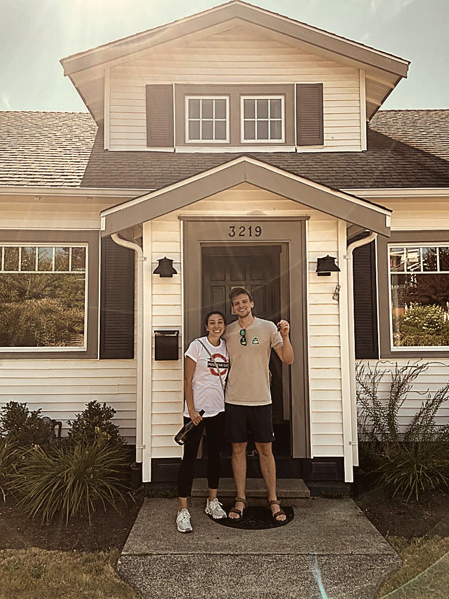 A smiling couple holding up the keys in front of their new home in Washington